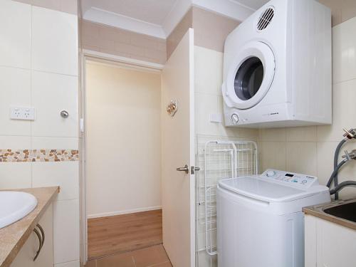 een kleine badkamer met een wasmachine en droger bij Kirra Vista Apartments Unit 18 in Gold Coast
