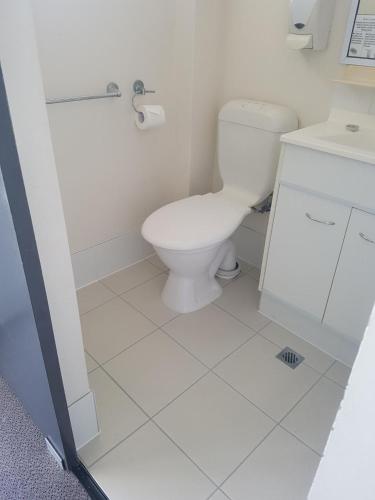 a white bathroom with a toilet and a sink at Chermside Court Motel in Brisbane