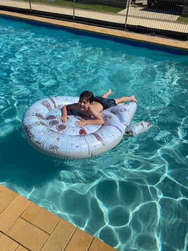 a young boy laying on an inner tube in a swimming pool at Geelong Surfcoast Hwy Holiday Park in Mount Duneed