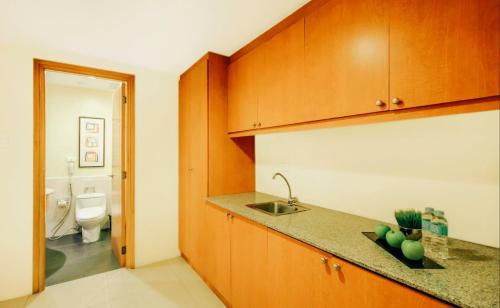 a kitchen with wooden cabinets and a sink and a toilet at Greenhills Elan Hotel Modern in Manila