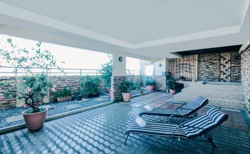 a patio with two chairs and a balcony with plants at Greenhills Elan Hotel Modern - Newly Renovated in Manila
