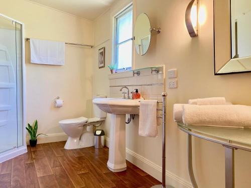 a bathroom with a sink and a toilet and a mirror at Eugenie Cottage 1930s Art Deco in Bright