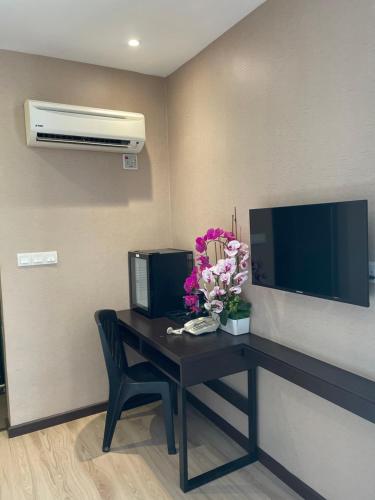 a room with a table with flowers and a tv at Geo Boutique Hotel - Seri Kembangan in Seri Kembangan