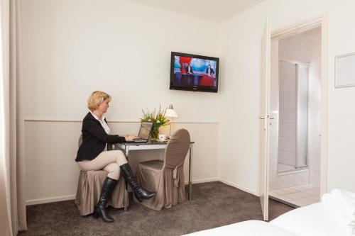 a woman sitting at a table with a laptop at Hotel Stad en Land in Alkmaar