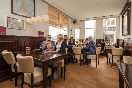 a group of people sitting at a table in a restaurant at Hotel Stad en Land in Alkmaar
