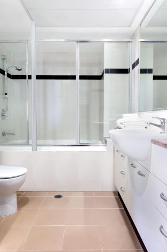 a white bathroom with a shower and a sink and a toilet at Mantra on Mary in Brisbane