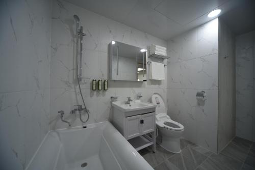 a bathroom with a tub and a sink and a toilet at Haeundae Central Hotel in Busan