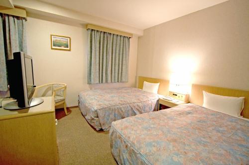 a hotel room with two beds and a flat screen tv at Hotel Central Sendai in Sendai