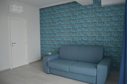 a blue couch in a room with a wall at Velier Apartments 38 and 49 in Mamaia