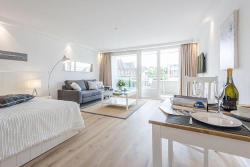 um quarto branco com uma cama e uma sala de estar em Hanseatenhaus Whg 1 em Westerland