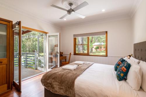 a bedroom with a large bed and a balcony at Bay and Bush Cottages Jervis Bay in Huskisson