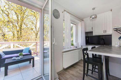 a kitchen and a living room with a table and chairs at Green Park Rentyear Apartments in Sopot