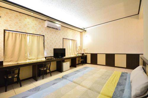 a room with a bed and a desk and a tv at Luyi Ludao B&B in Green Island