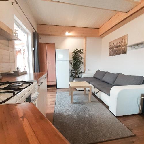 a living room with a white couch and a kitchen at Apartamenty - Mazurski Zaścianek - Kruklanki in Kruklanki