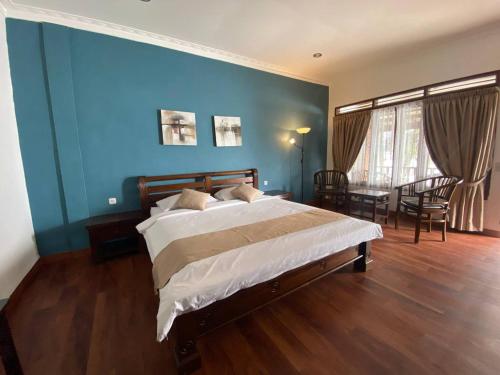 a bedroom with a large bed and a blue wall at Toledo Inn in Tuk Tuk