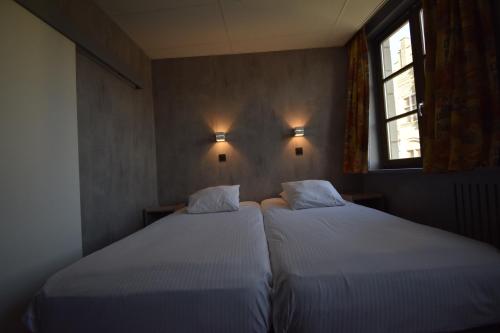 two twin beds in a small room with two windows at Hotel Gasthof 't Zweerd in Ieper