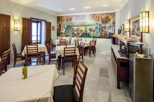 a restaurant with tables and chairs and a painting on the wall at Hotel Las Casas del Duque in Osuna