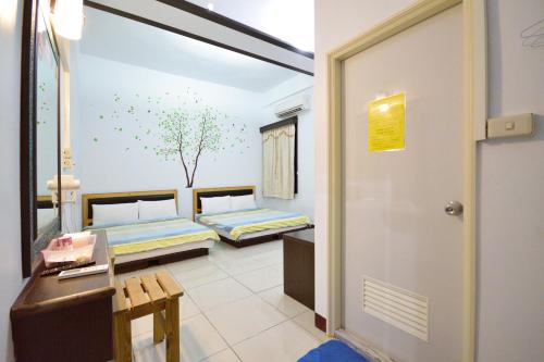 a room with two beds and a desk and a door at Luyi Ludao B&B in Green Island