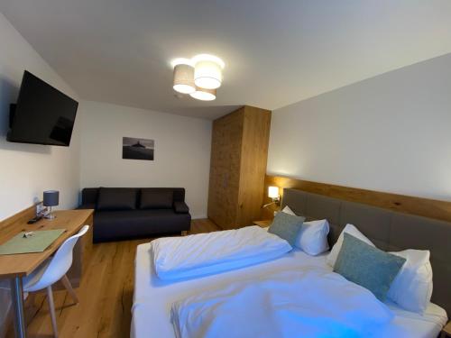 a bedroom with a bed and a desk and a couch at Apartments Freitag - H1 in Winden am See