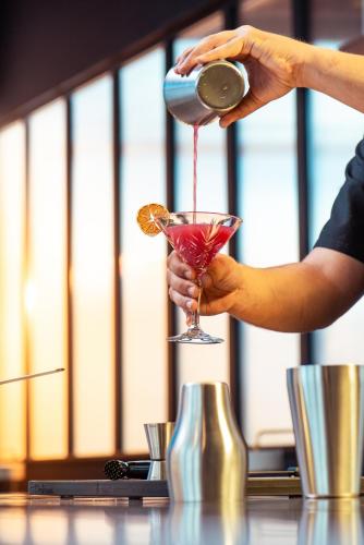a person pouring a drink into a martini glass at Novotel Annemasse Centre - Porte de Genève in Annemasse