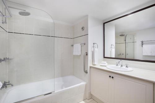 uma casa de banho branca com uma banheira e um lavatório em Mantra Esplanade em Cairns