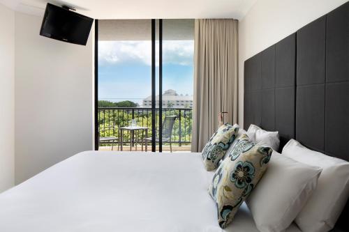 a bedroom with a large white bed with a balcony at Mantra Esplanade in Cairns