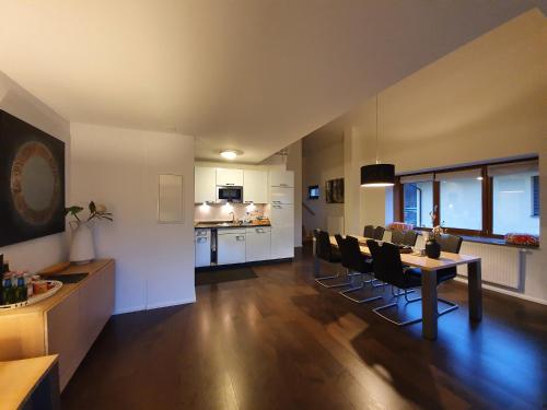 a living room with a table and chairs and a kitchen at Luxuriöses Galerie-Penthouse direkt am Walensee in Unterterzen
