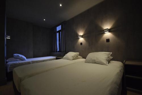 two beds in a room with lights on the wall at Hotel Gasthof 't Zweerd in Ypres