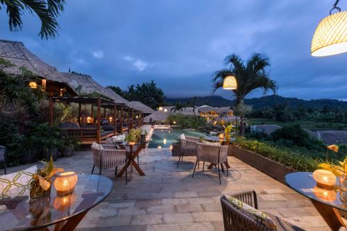 a patio area with tables and chairs and umbrellas at Samanvaya Luxury Resort & Spa - Adults Only in Sidemen