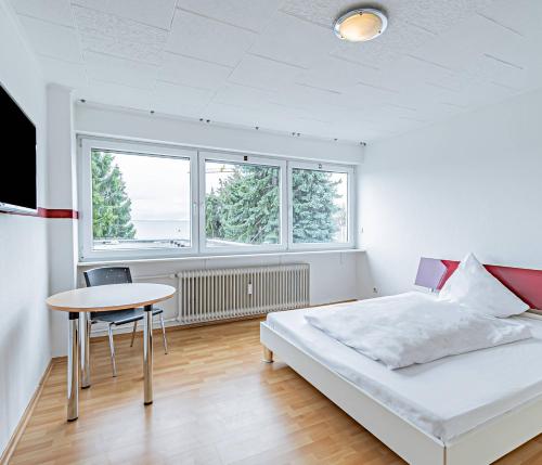 um quarto com uma cama, uma mesa e 2 janelas em Hotel Tannenblick em Bad Vilbel