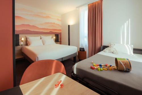 a hotel room with two beds and a table at Novotel Annemasse Centre - Porte de Genève in Annemasse