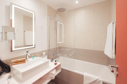 a bathroom with a sink and a bath tub at Novotel Annemasse Centre - Porte de Genève in Annemasse