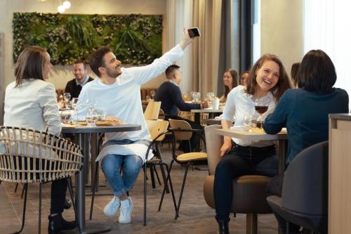 a man taking a picture of a woman at a restaurant at Novotel Annemasse Centre - Porte de Genève in Annemasse