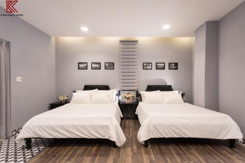 two beds in a room with white walls at TTR Skypool View Hotel in Da Lat