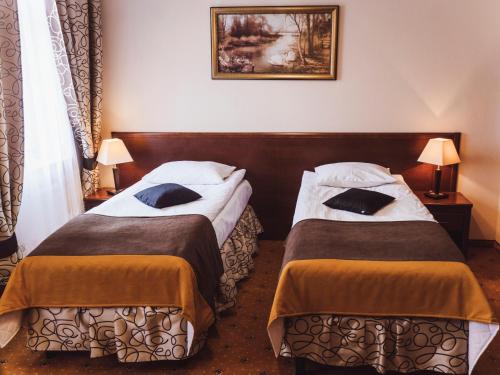 two beds in a hotel room with two lamps at Hotel Osjann in Biała Podlaska