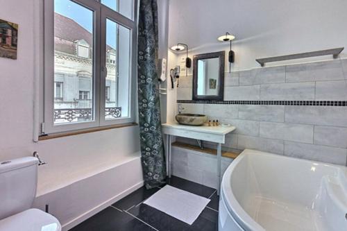 a bathroom with a tub and a toilet and a sink at Les Appartements Fénelon in Le Cateau