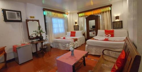 a hotel room with two beds and a table at RedDoorz Plus @ Evangeline Beach Resort in Pagudpud