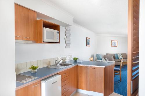 a kitchen with a sink and a microwave at Mantra Hervey Bay in Hervey Bay