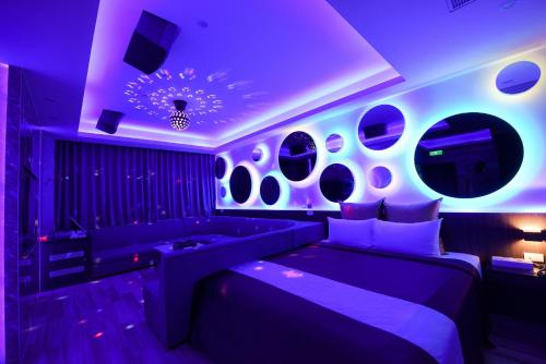 a purple room with a bed and a couch at I-Like Motel in Pingzhen
