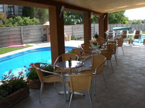 een patio met tafels en stoelen naast een zwembad bij Penzión ONE in Dolný Ohaj