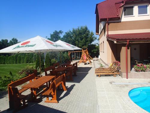 a patio with wooden tables and benches and a playground at Penzión ONE in Dolný Ohaj