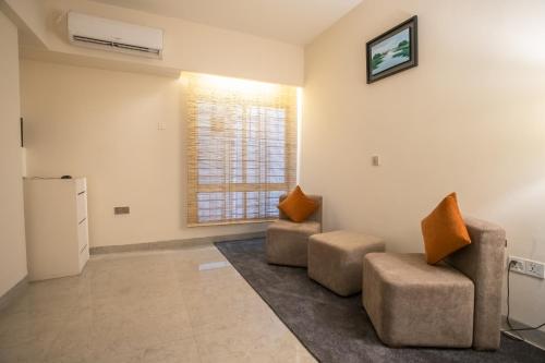 a living room with two chairs and a window at Jatra Flagship Chattogram City Centre in Chittagong