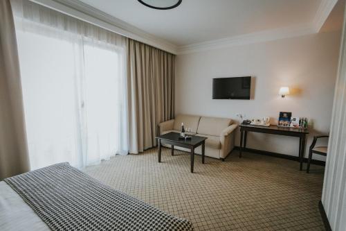 a hotel room with a bed and a couch and a television at Hotel Toscania in Włoszakowice