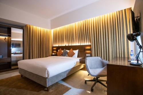 a bedroom with a bed and a desk and a chair at Jatra Flagship Chattogram City Centre in Chittagong