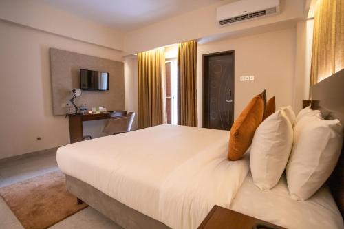 a bedroom with a large white bed with pillows at Jatra Flagship Chattogram City Centre in Chittagong