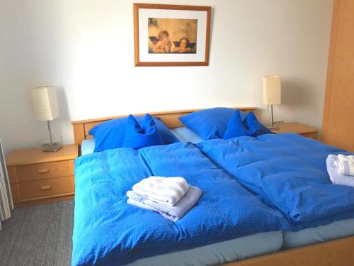 ein blaues Bett mit blauer Bettwäsche und Handtüchern darauf in der Unterkunft Gästehaus am Deich in Juist