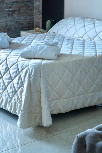 a white bed with white sheets and pillows on it at Hotel San Luca in Battipaglia