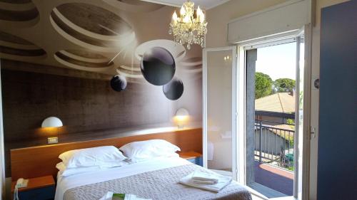 a bedroom with a bed and a window and a chandelier at Hotel President in Cervia