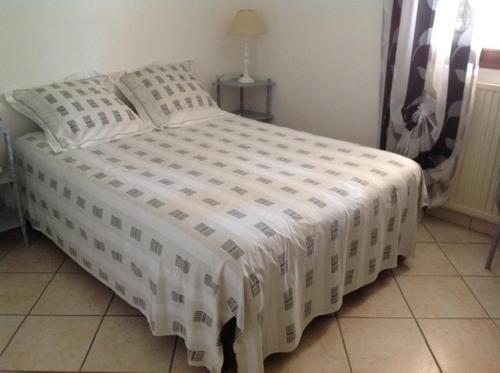 - un lit avec une couette blanche dans une chambre dans l'établissement Appartement Rez de chaussé, à Bollène