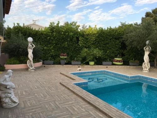 - une piscine avec 2 statues dans une cour dans l'établissement Appartement Rez de chaussé, à Bollène